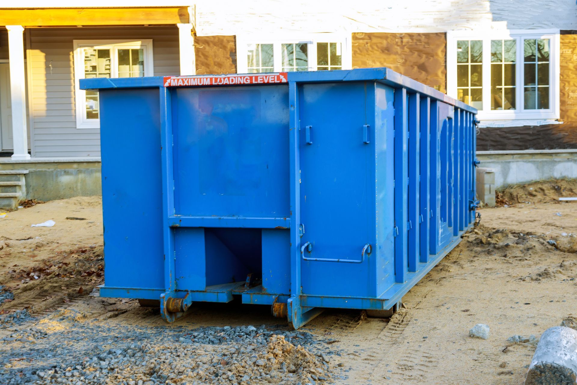 A trash dumpster outside a residential construction site.