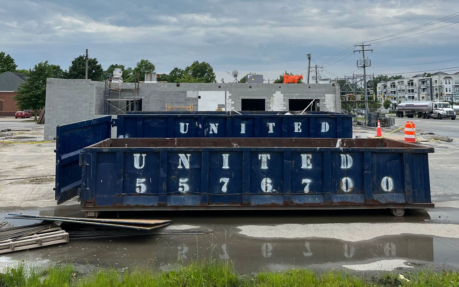 A blue dumpster is sitting in front of a house under construction
