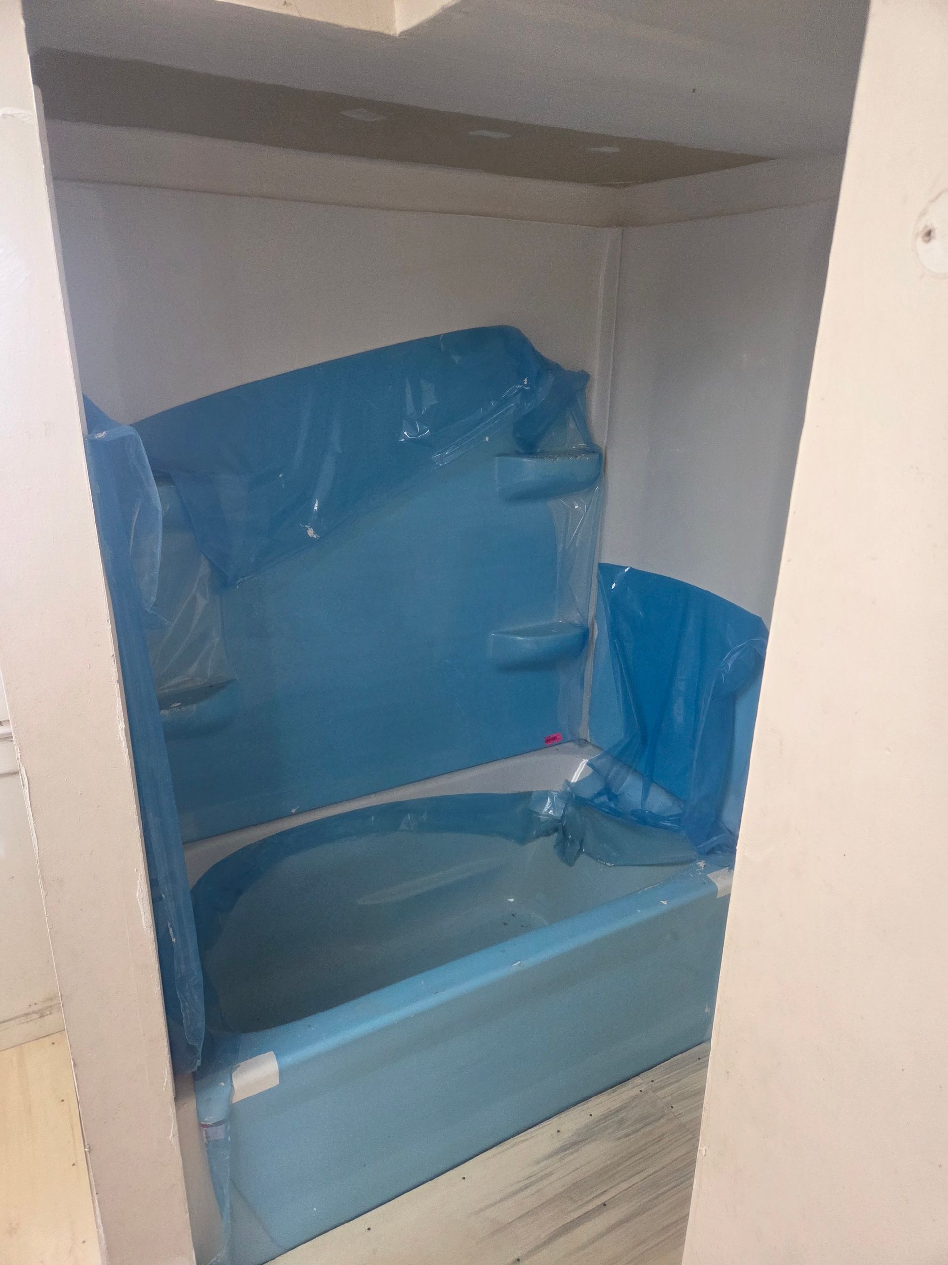 Blue inflatable bathtub setup in a small bathroom alcove