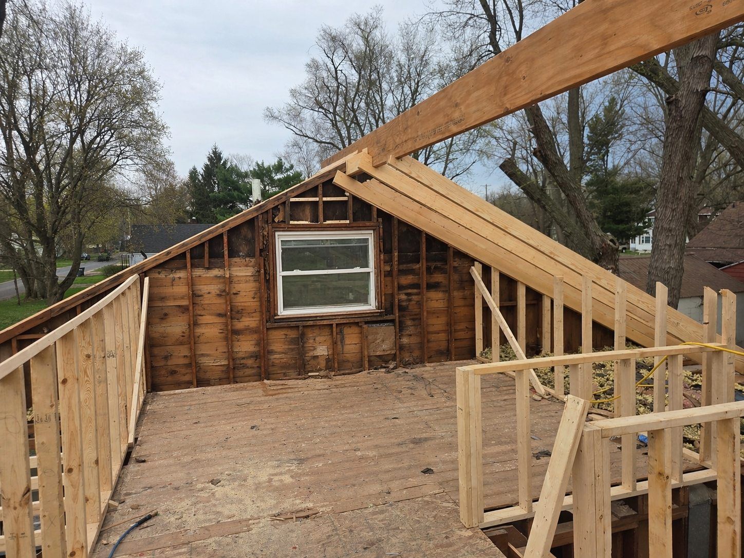 Partially built wooden shed framing with a small window and open roof under construction outdoors