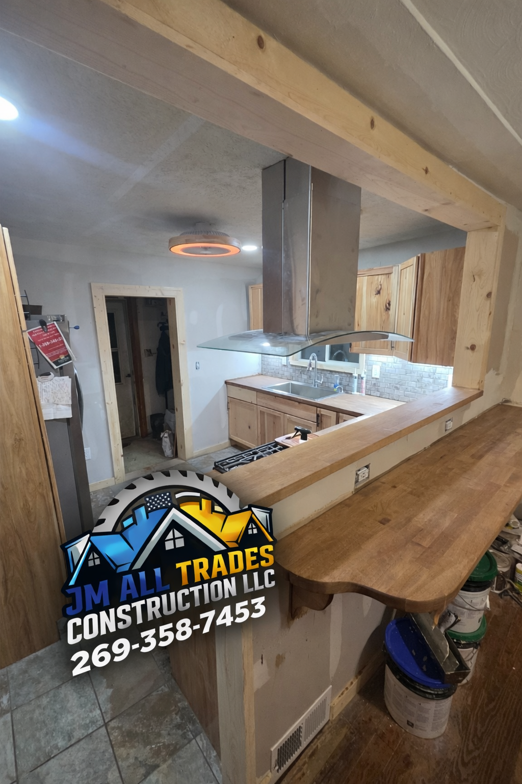Wood-framed kitchen under renovation, with exposed beams and stainless steel range hood.