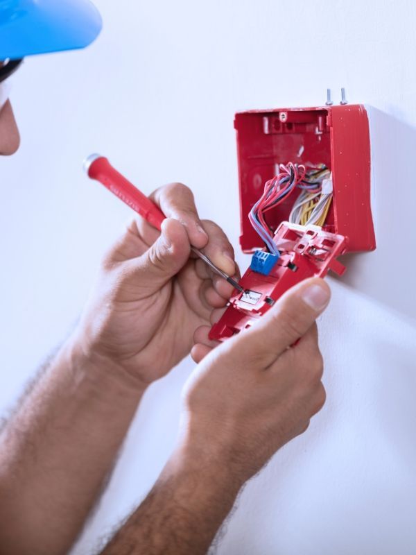 Electrician wiring a fire alarm system in a commercial building