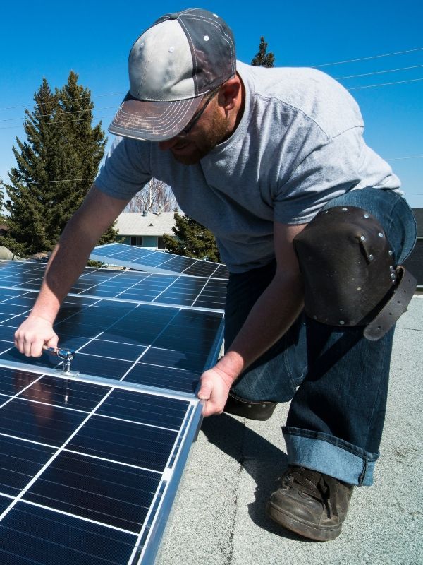 Electricians installing solar panels on an industrial rooftop