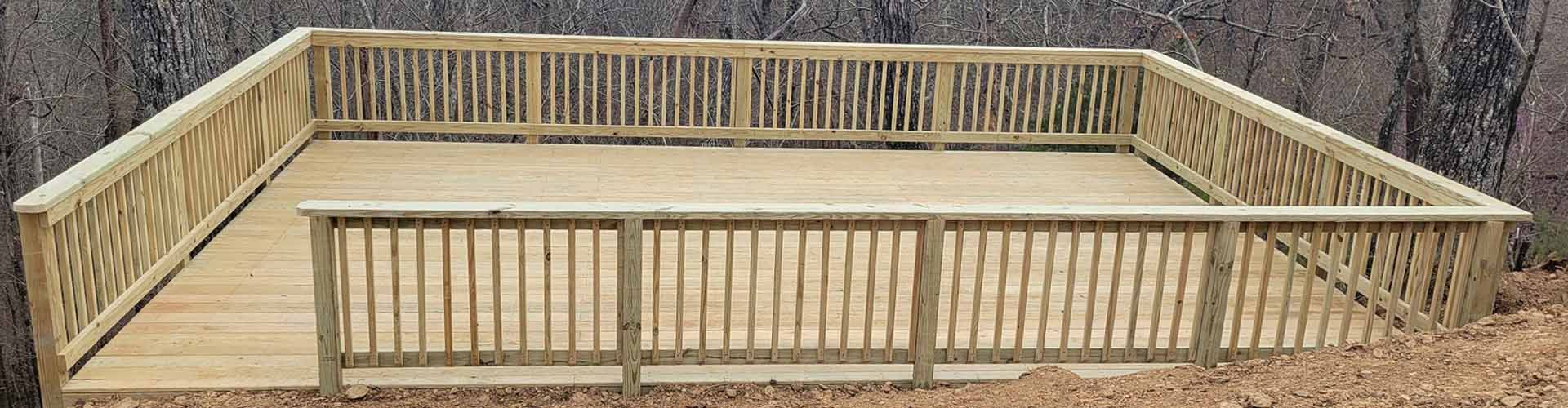 Wooden deck with railings. Brown wood, square shape, surrounded by rocky terrain.