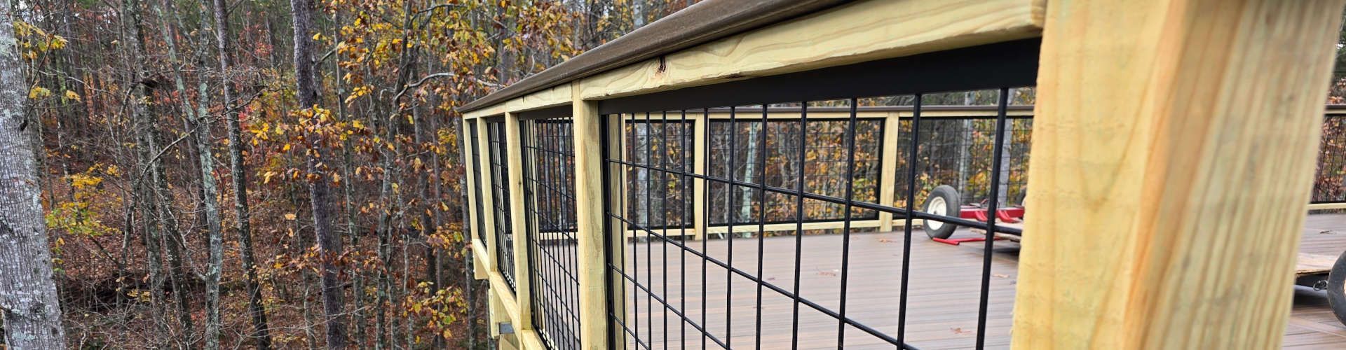 Wooden structure with wire mesh railings, set among trees with fall foliage.