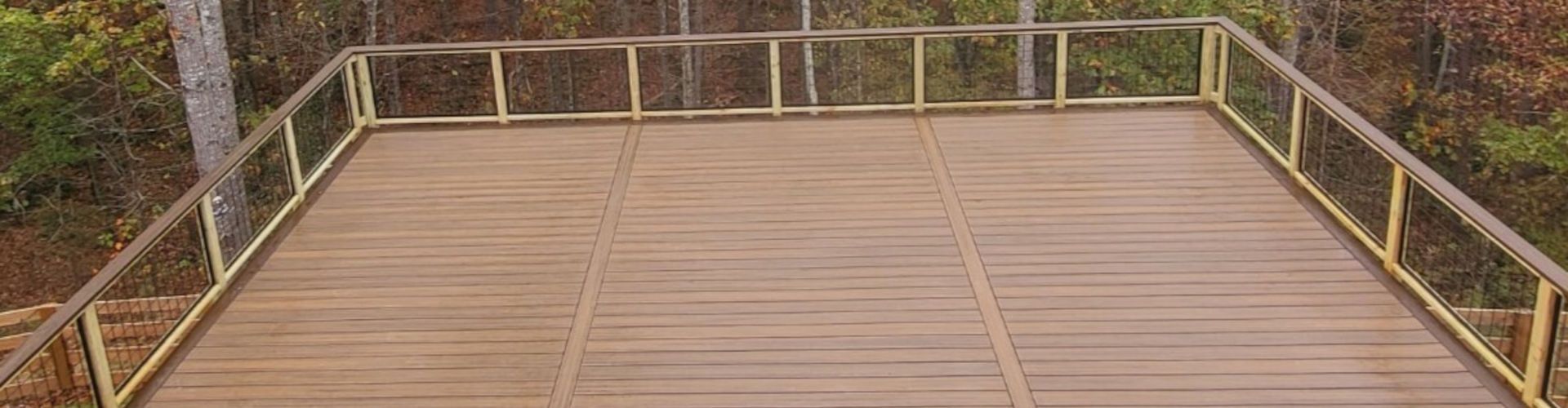 Wooden platform with yellow railing in a wooded setting.