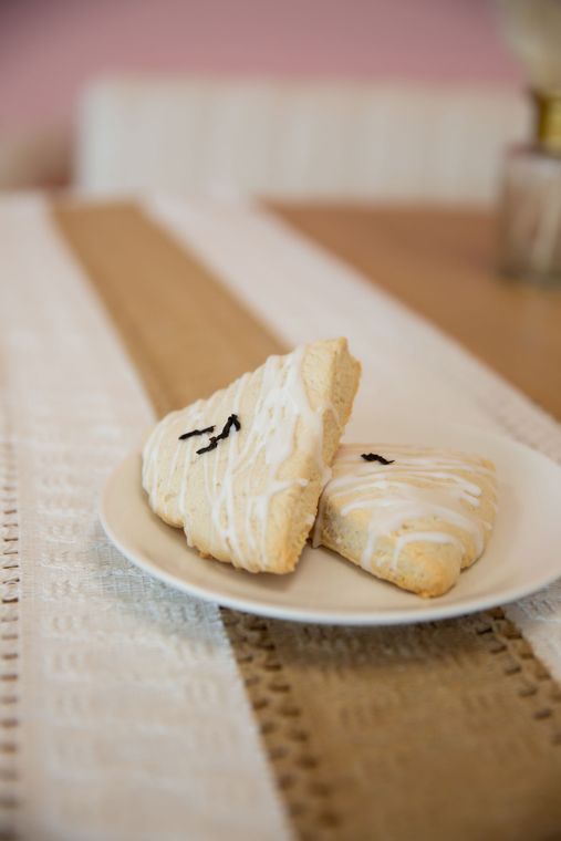 Latte with layered coffee and foam beside a pastry on a wooden board.