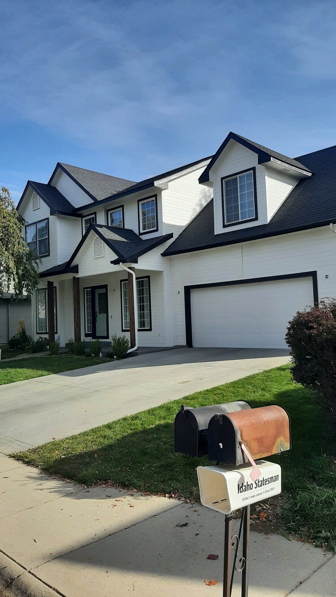 Suburban house with a two-car garage, driveway, and a mailbox in the foreground.