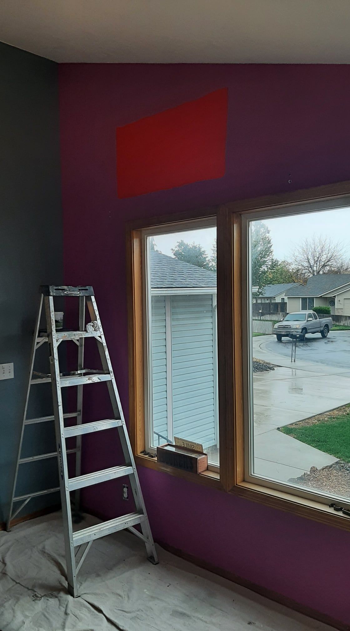 Interior room with purple walls, a ladder by the window, and a red painted patch near the ceiling.