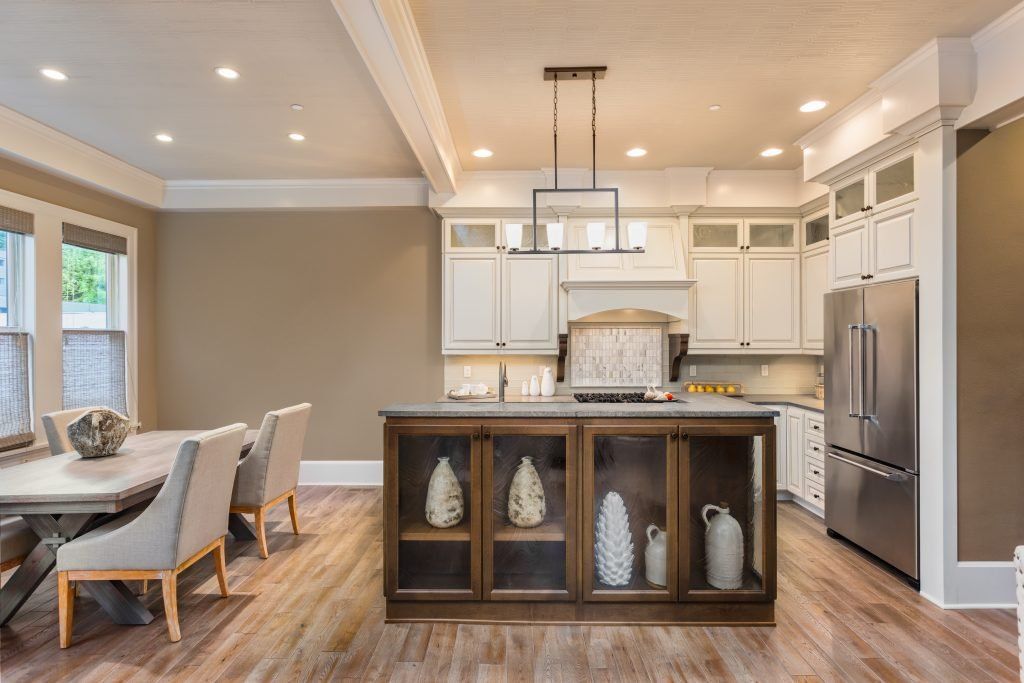 Bright modern kitchen with white cabinets, island, wood floors, and stainless steel refrigerator