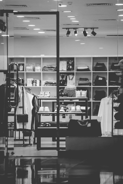RETAIL Zwart-wit interieur van een winkel met kledingrekken, spiegels en een centraal displayrek.