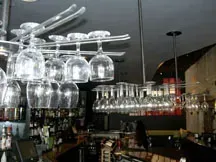 A bar with a lot of wine glasses hanging from the ceiling.