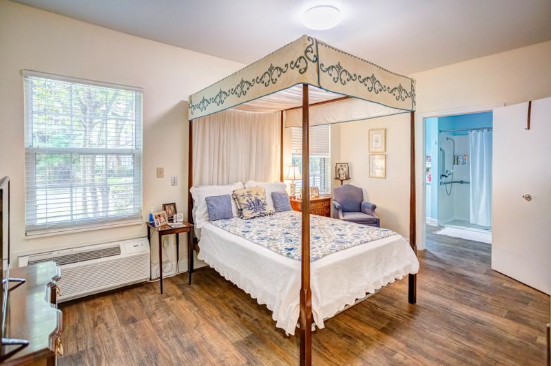 A bedroom with a canopy bed and a large window.