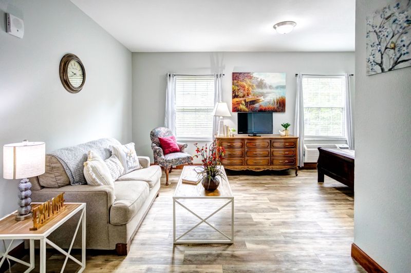 A living room with a couch , chair , coffee table and television.