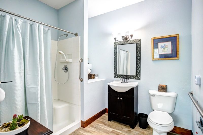 A bathroom with a toilet , sink , shower and mirror.