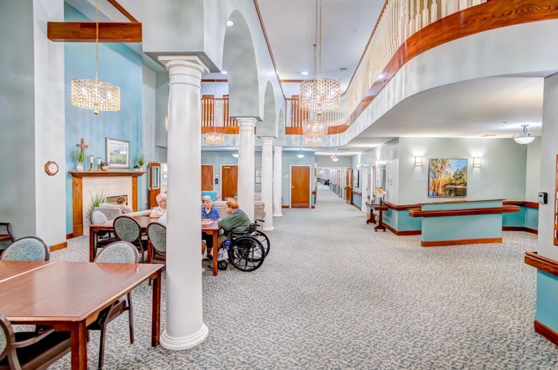 A man in a wheelchair is sitting at a table in a dining room in a nursing home.