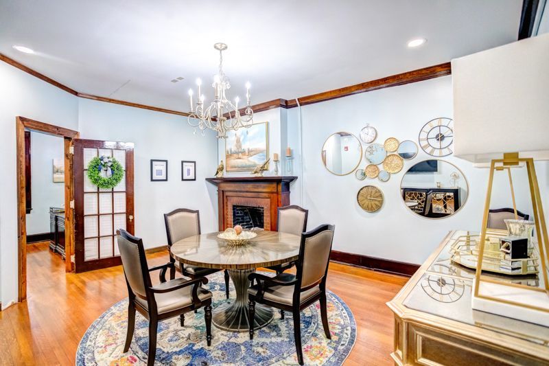 A dining room with a round table and chairs and a fireplace.