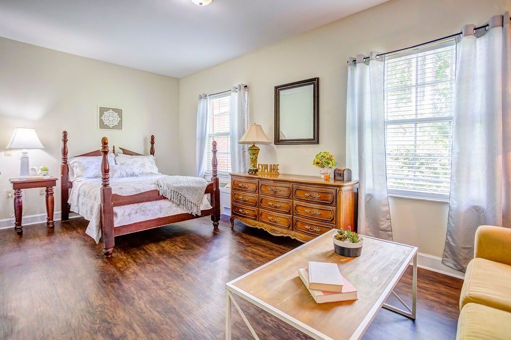 A bedroom with a bed , dresser , coffee table and couch.