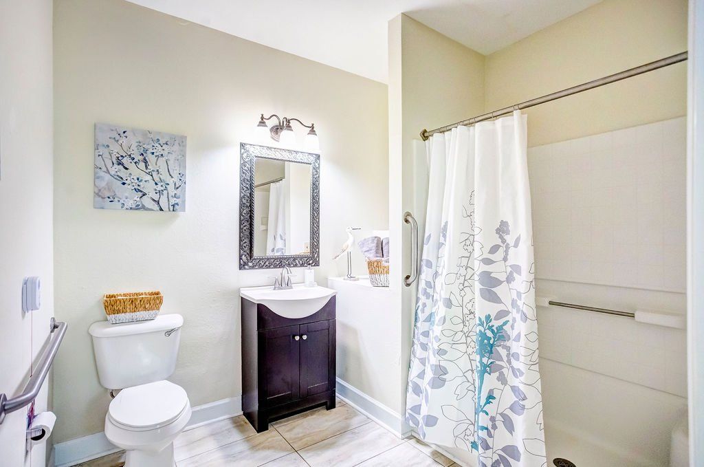 A bathroom with a toilet , sink , mirror and shower curtain.