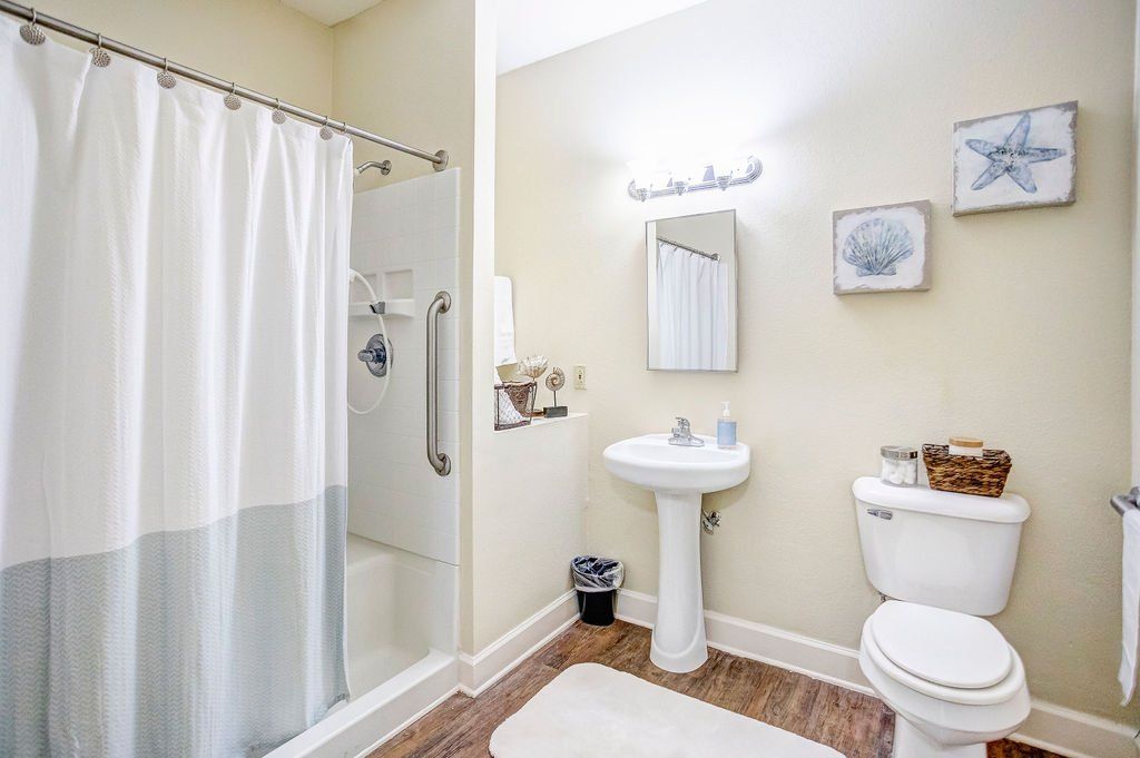 A bathroom with a toilet , sink , shower and mirror.