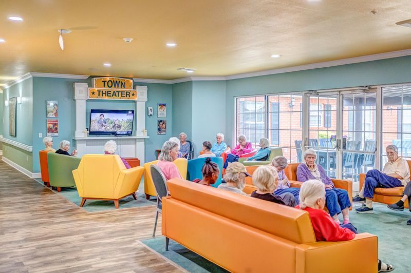A group of elderly people are sitting on couches in a living room.
