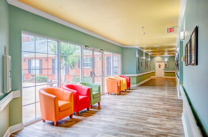 A long hallway with colorful chairs and a large window.