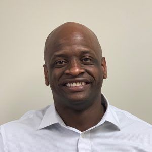 A bald man in a white shirt is smiling for the camera.