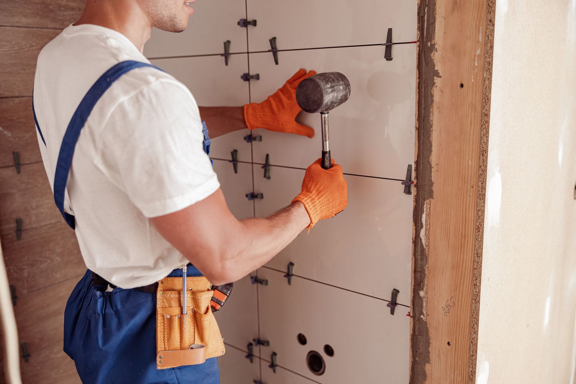 Male worker installing ceramic wall tile in house