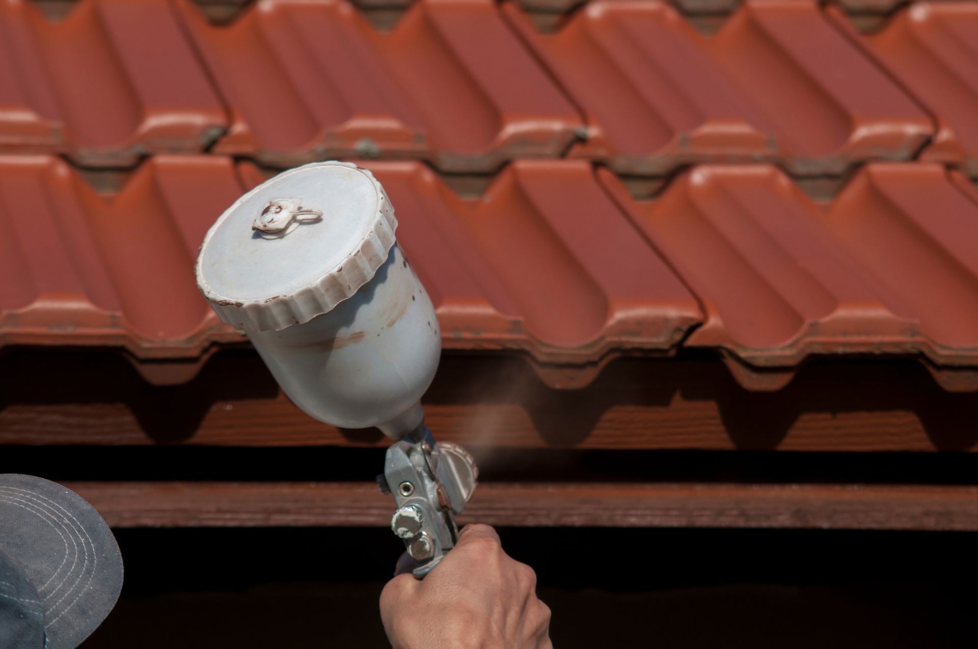 Hand spraying sealant onto red roof tiles with a paint sprayer Hand spraying sealant onto red roof tiles with a paint sprayer