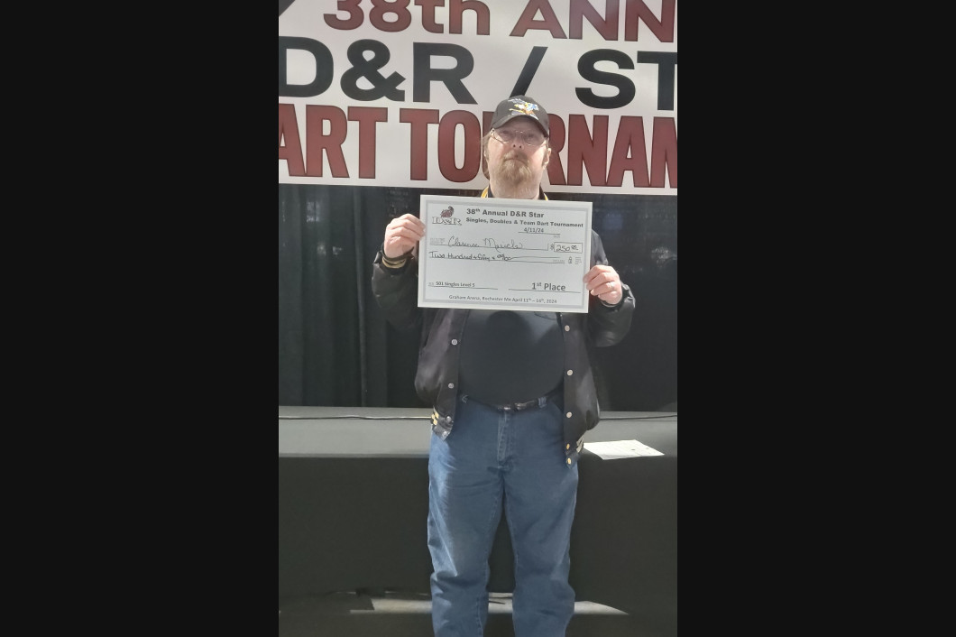 Man in a leather jacket holding a large check at the 38th Annual D&R/ST Art Tournament.