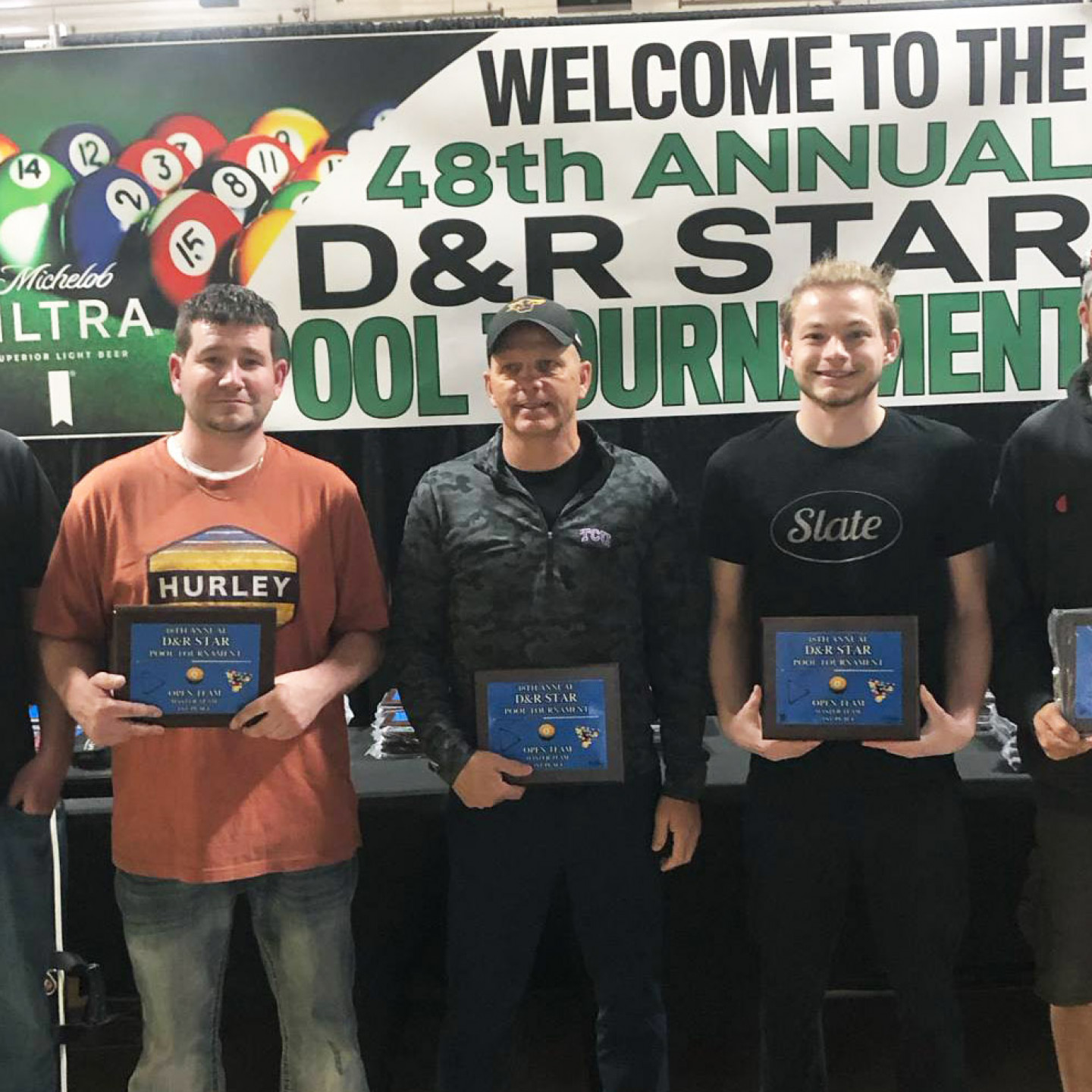 Five people holding plaques in front of a banner that says 
