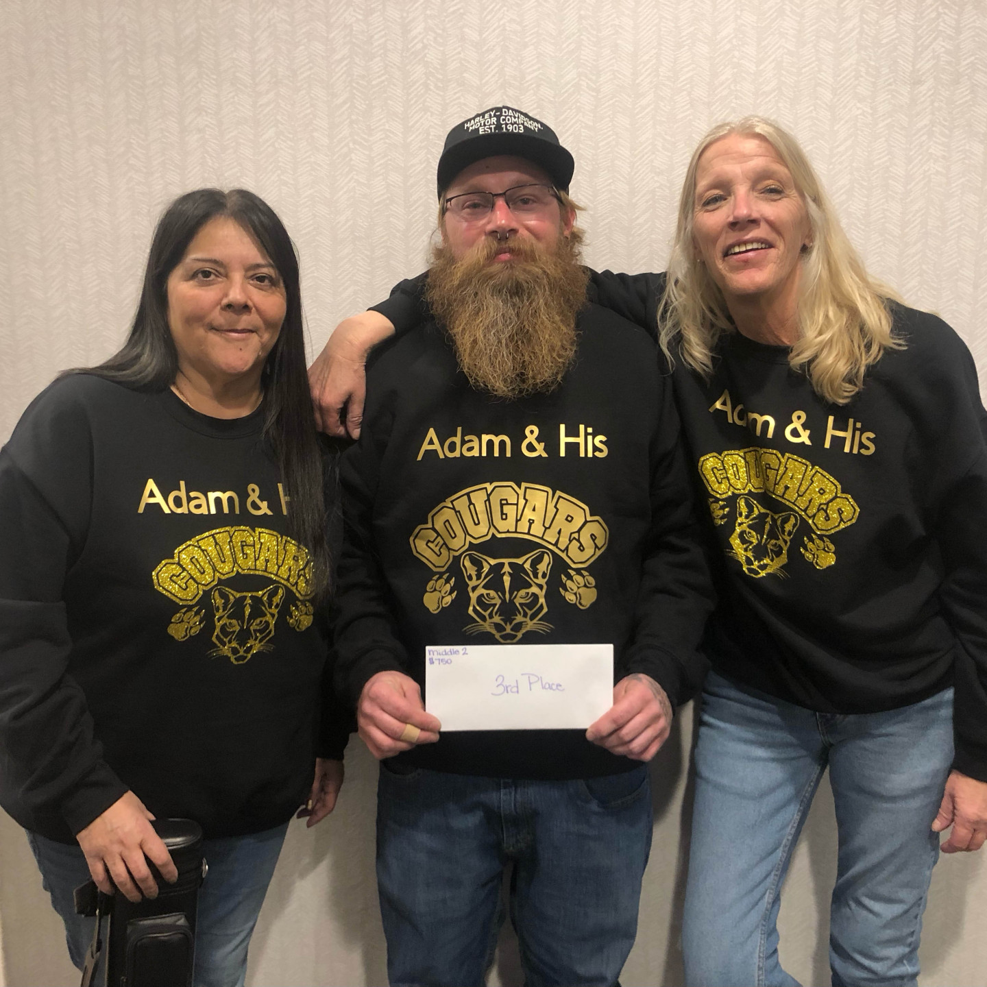 Three people wearing matching black sweatshirts that read 