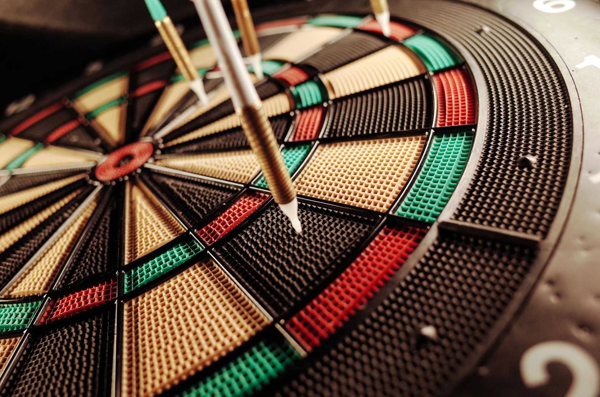 Dartboard with several darts in the board, mostly in the higher scoring areas.