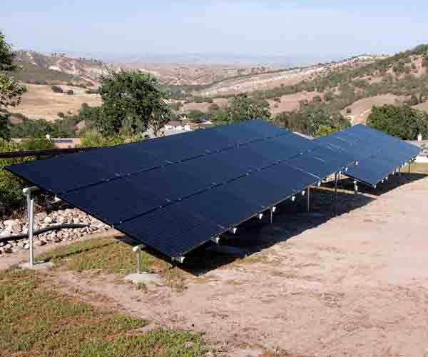 A row of solar panels sitting on top of a dirt field.