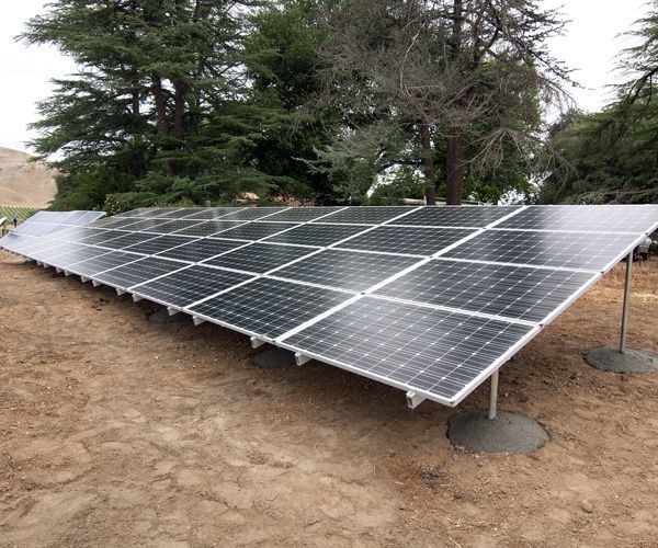A row of solar panels sitting on top of a dirt field.