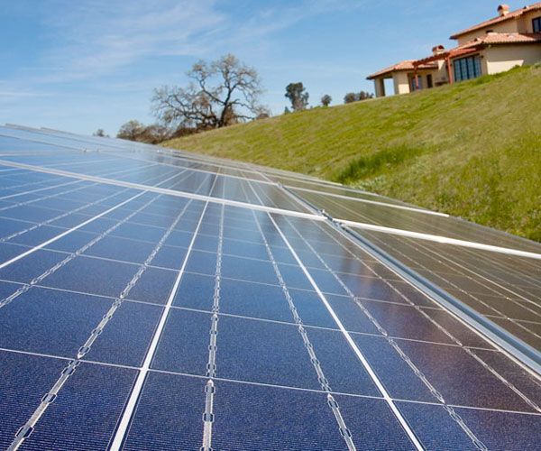 A row of solar panels sitting on top of a grassy hill