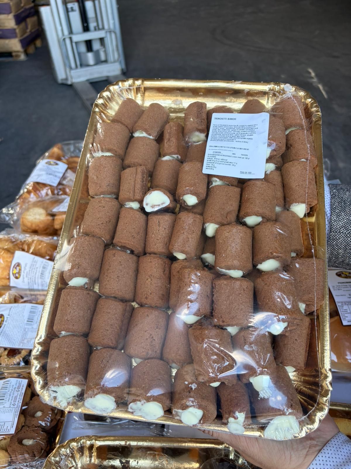 Vassoio di pasticcini al cioccolato con ripieno bianco, avvolti in plastica trasparente.