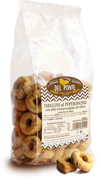 Mano che regge un sacchetto di taralli su una bancarella del mercato. Sono visibili altri prodotti da forno e un carrello elevatore.