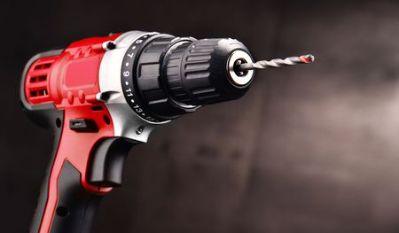 Trapano a batteria rosso con punta, isolato su sfondo scuro.