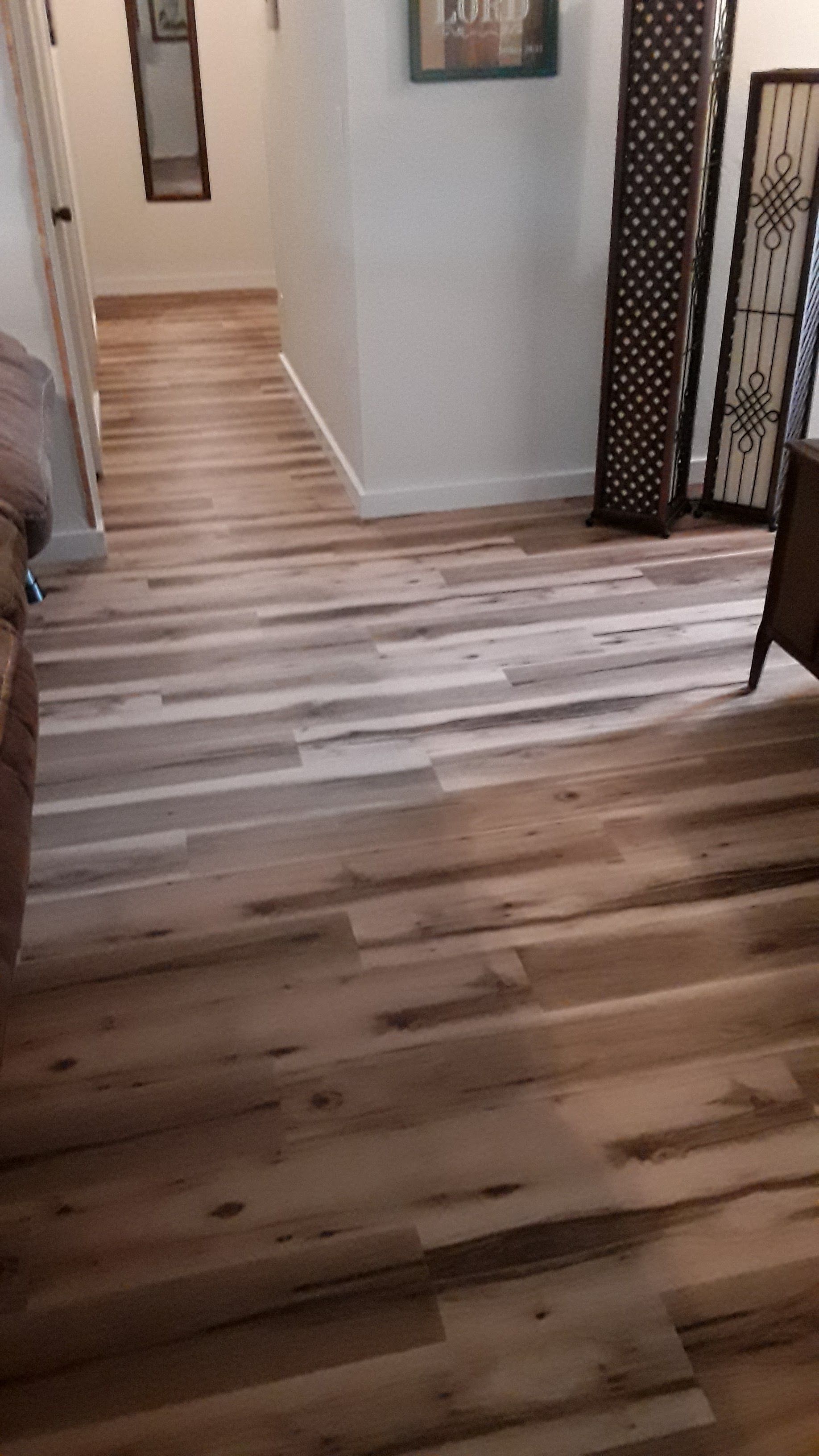 Wooden hallway with light flooring, white walls, and a decorative room divider on the right.