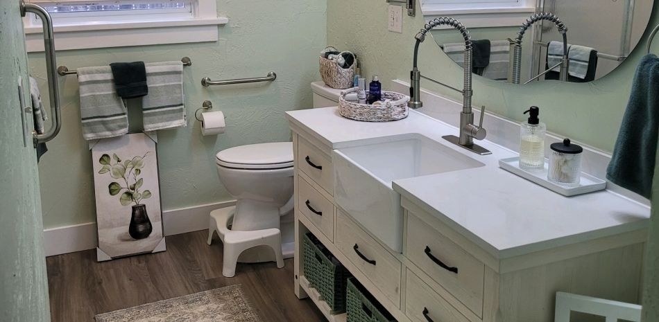 Bright bathroom vanity with double sinks, white cabinets, toilet, and light green walls