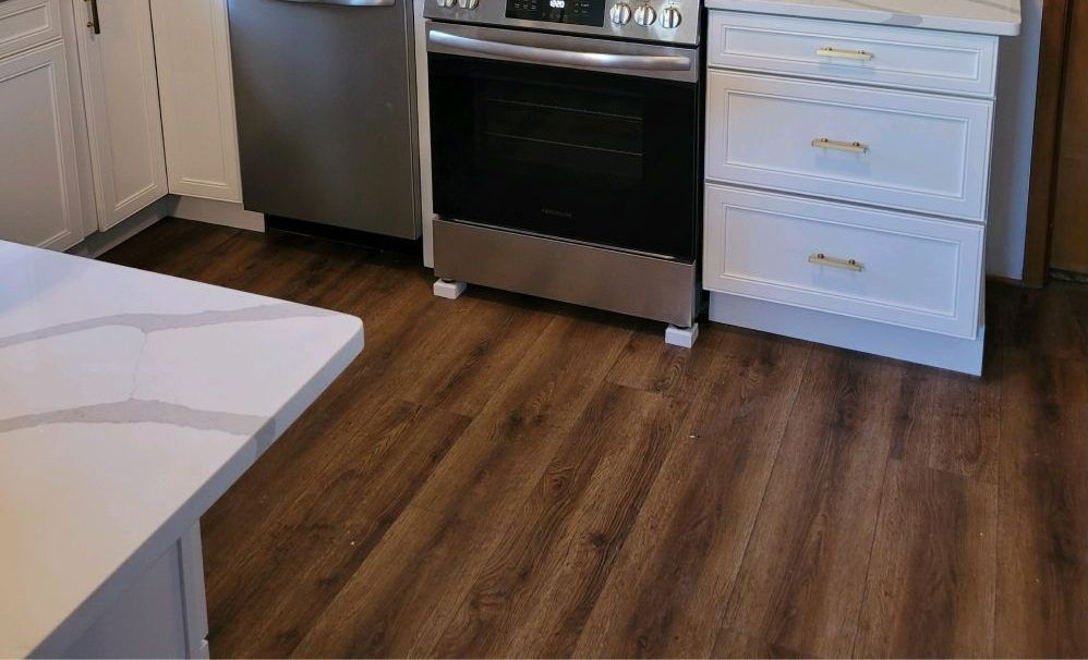 Modern kitchen with stainless steel oven, white cabinets, and wood-look flooring