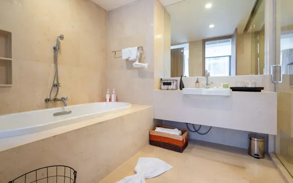 Bright modern bathroom with a bathtub, large vanity mirror, and beige tiled walls.