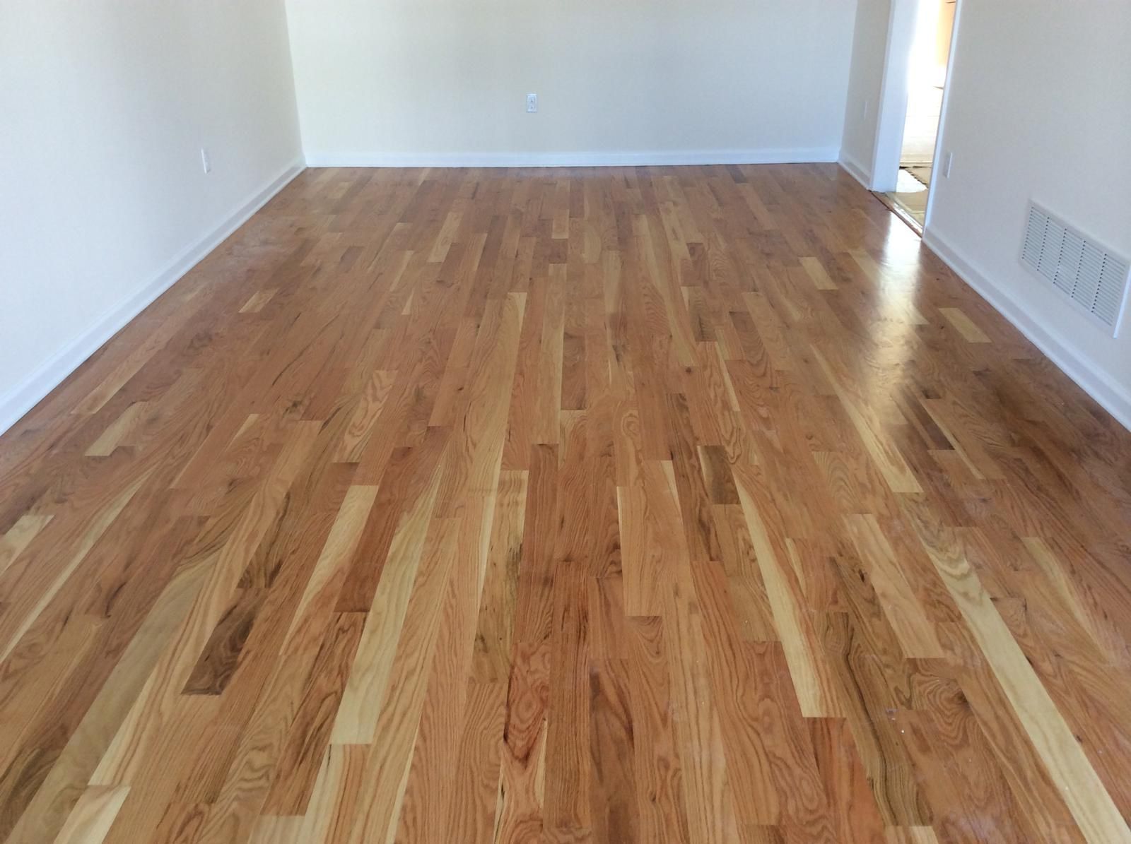Empty room with light walls and polished hardwood floor, viewed toward a doorway.