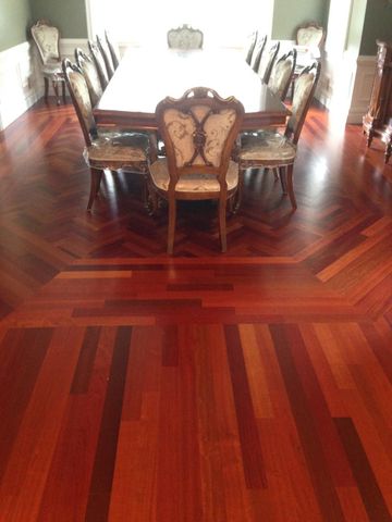 Formal dining room with a large wooden table, ornate chairs, and polished reddish hardwood floors.