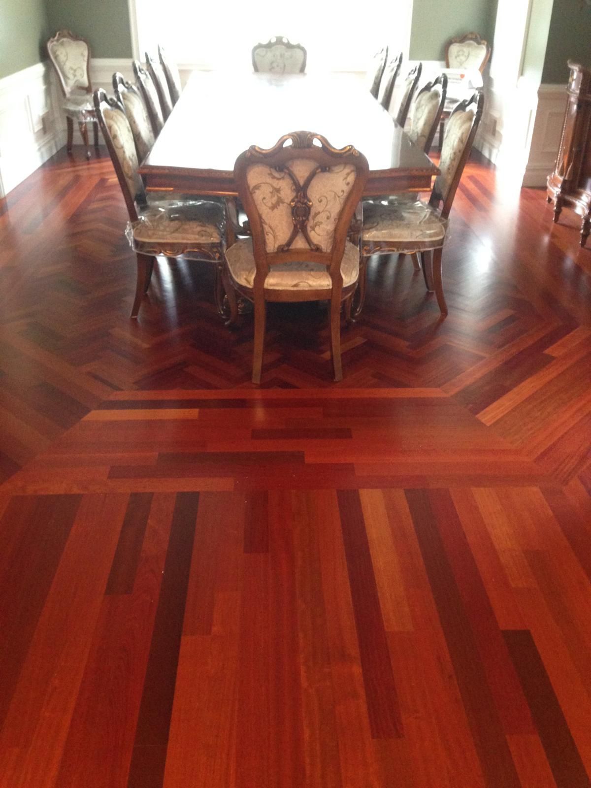 Dining room with a polished red hardwood floor and a long table surrounded by ornate chairs