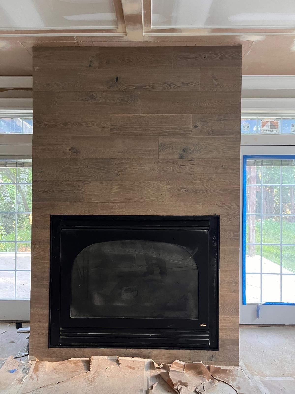 Modern fireplace with black insert and wood-paneled surround in a bright living room