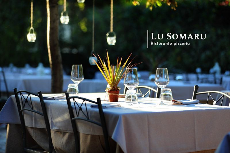 un ristorante è chiamato lu somaru e ha un tavolo pieno di bicchieri e posate