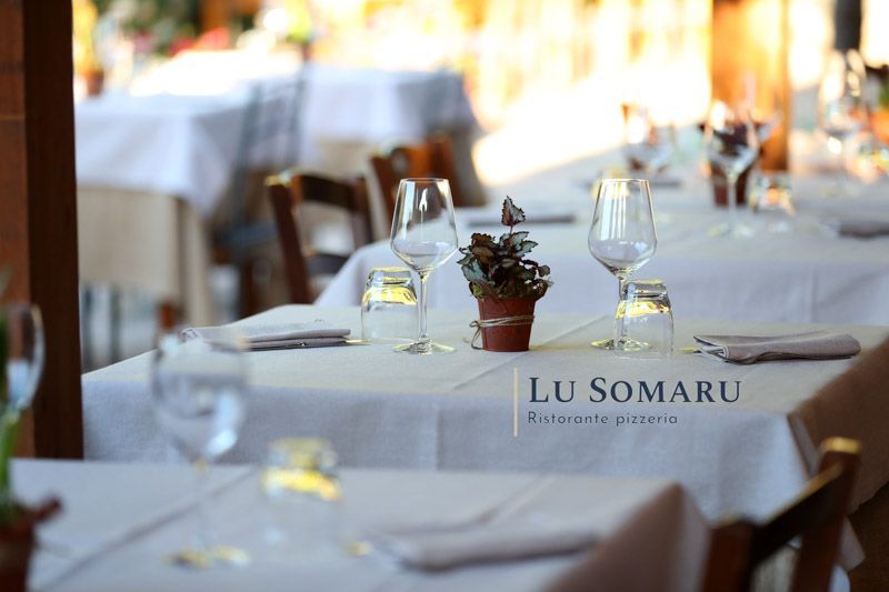 un ristorante è chiamato lu somaru e ha un tavolo pieno di bicchieri e tovaglioli