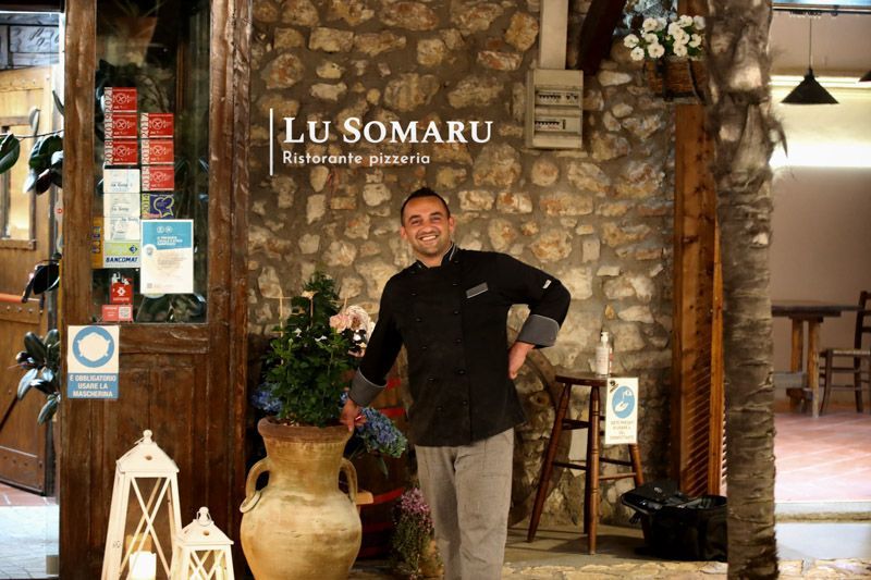 un uomo in piedi davanti a un ristorante chiamato lu somaru